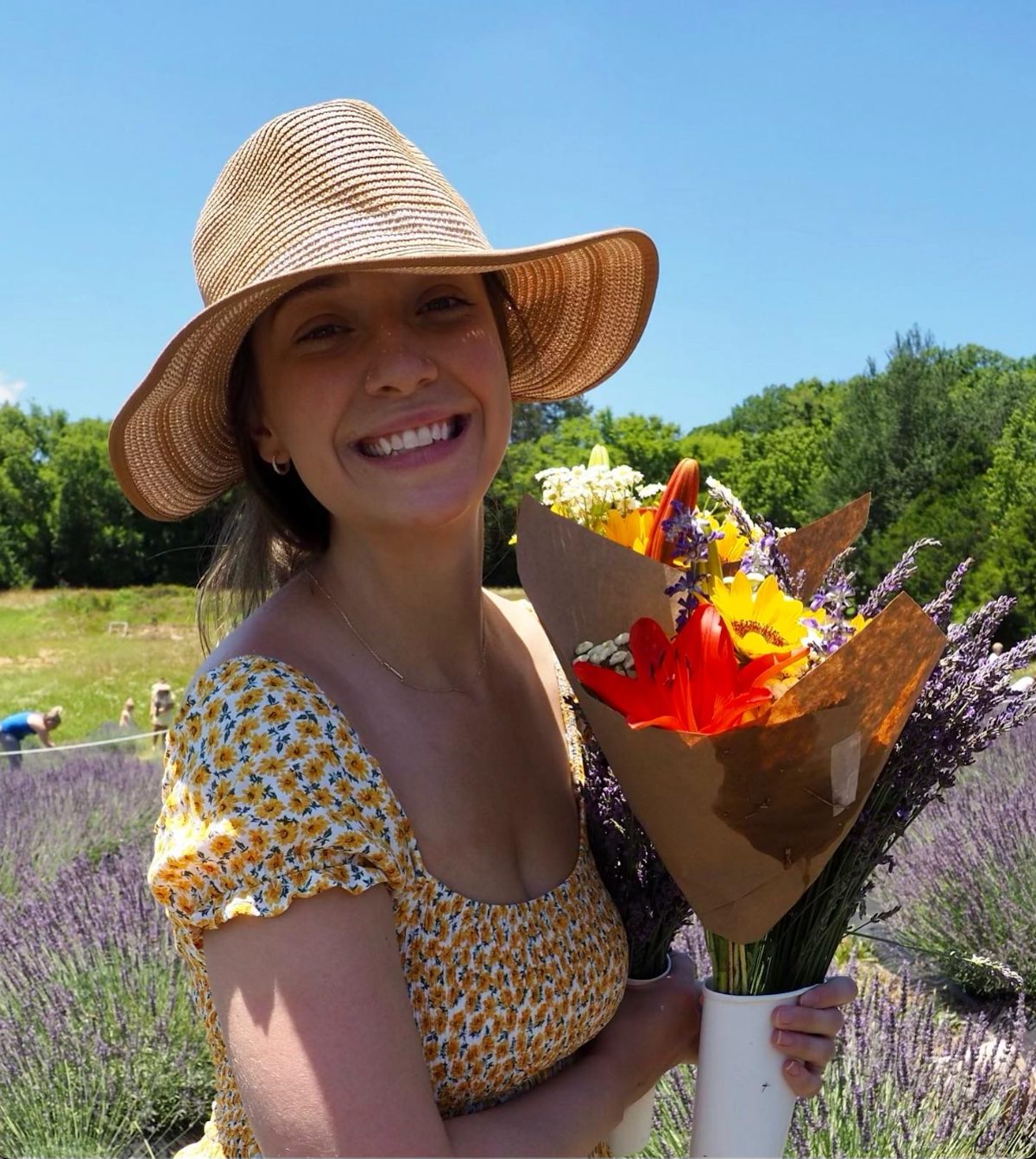 Hannah, founder of Point to Stitch, holding a bouquet in a lavender field