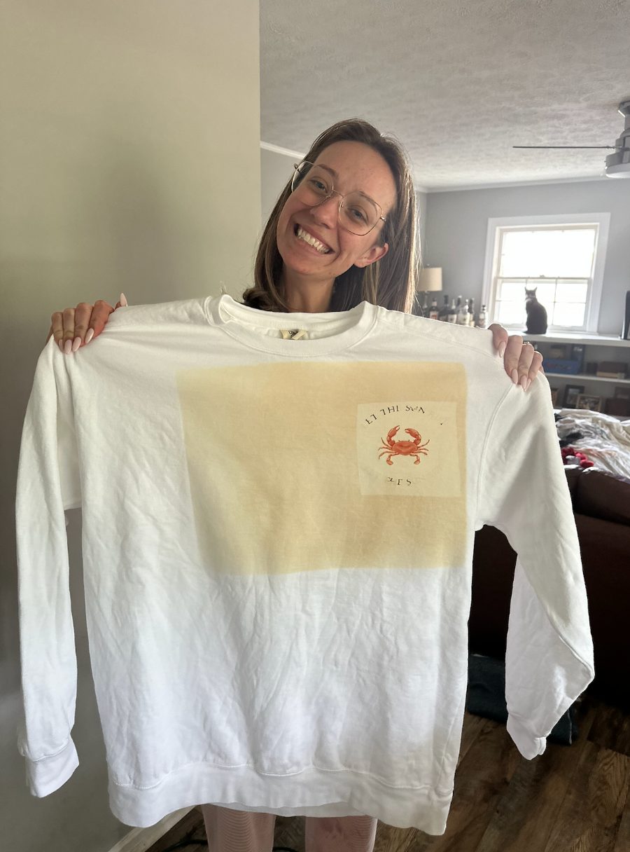 Holding up a hand-printed crab sweatshirt