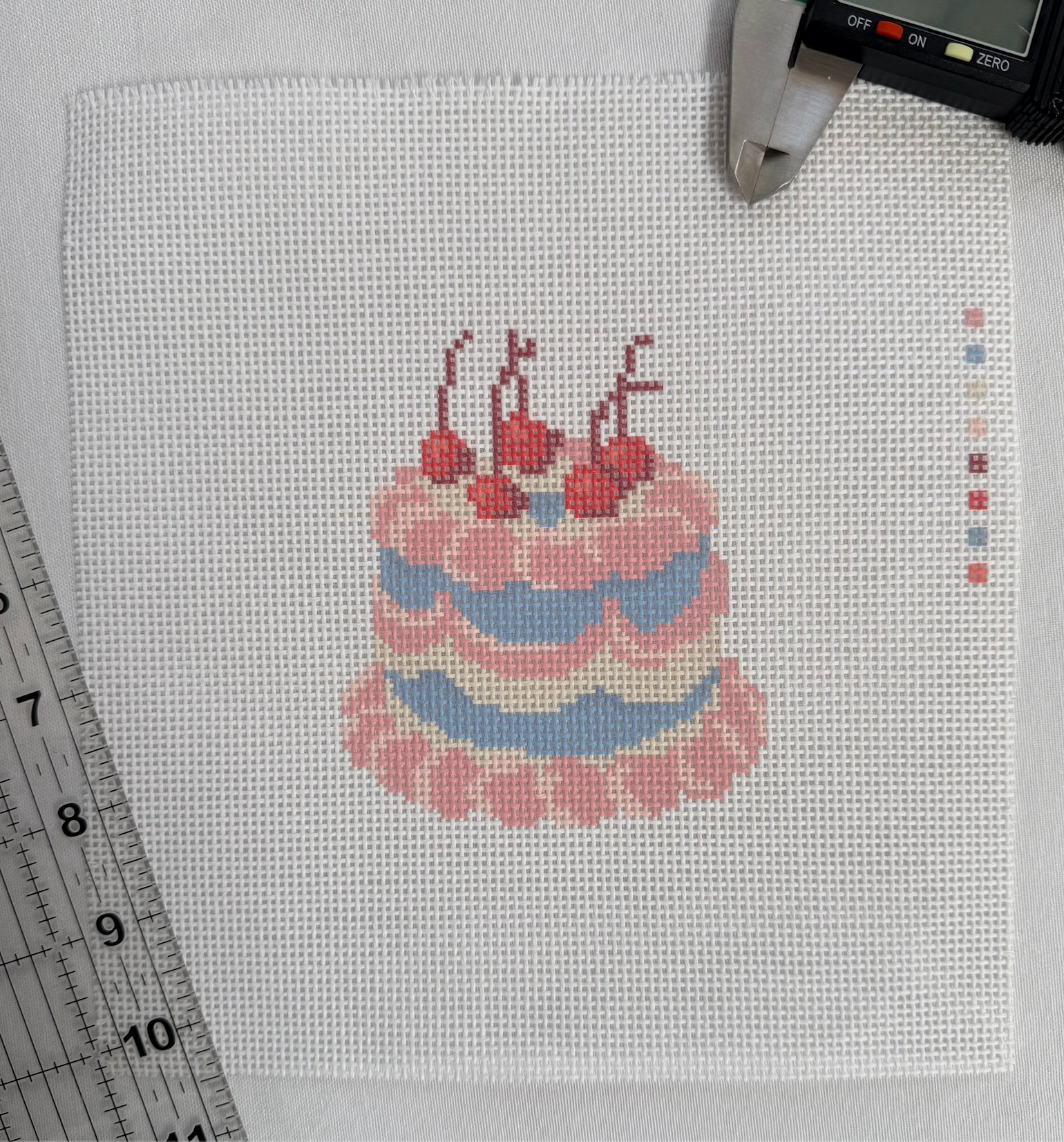 A printed cherry cake canvas in pinks and blues with its color key along the edge